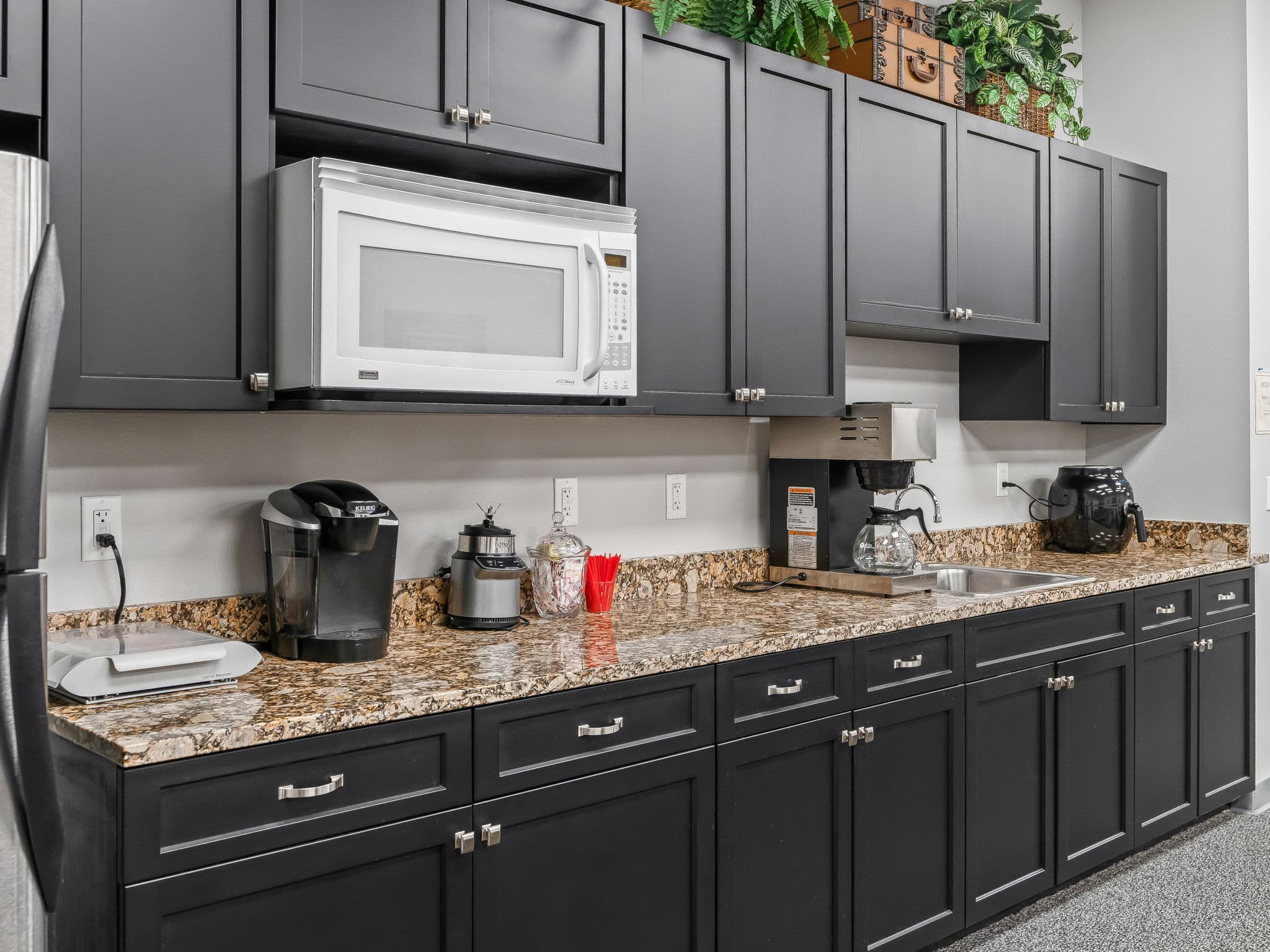 A modern kitchen featuring sleek black cabinets and elegant granite countertops.