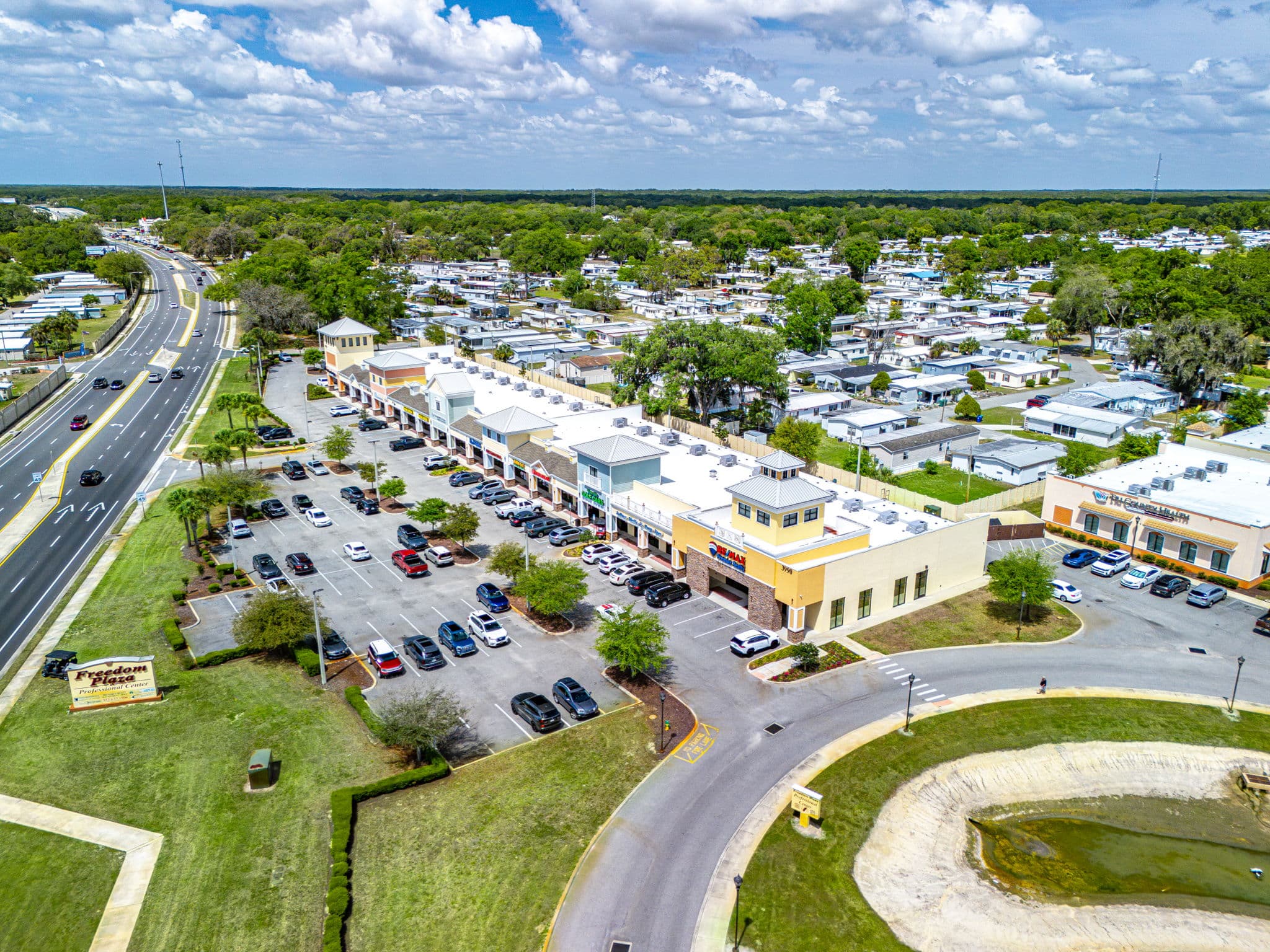 Aerial view of a shopping center featuring multiple parking lots and surrounding green spaces.