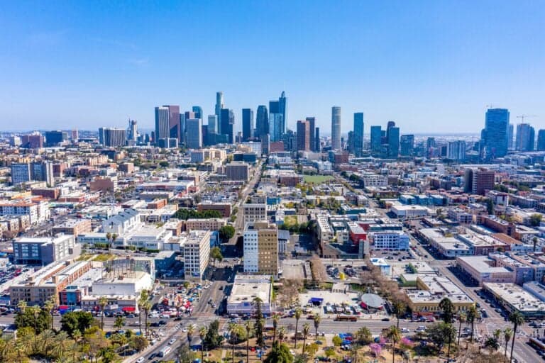 An expansive aerial view of the Downtown Los Angeles skyline under a clear blue sky, representing the broad reach of professional SEO and digital marketing services in Los Angeles, CA.