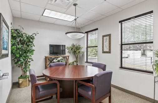 A conference room featuring a large table surrounded by several chairs, designed for meetings and discussions.